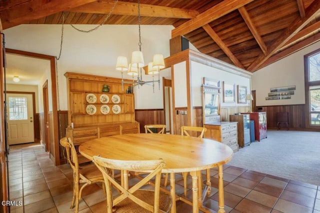dining space with vaulted ceiling with beams, light colored carpet, and wainscoting