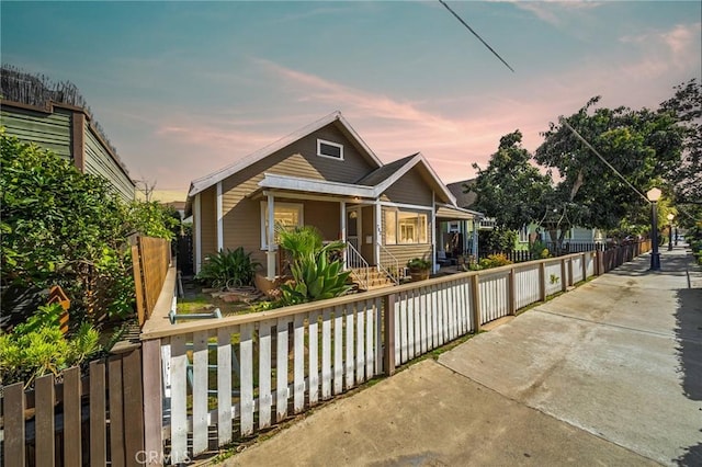 bungalow-style house with a fenced front yard and covered porch