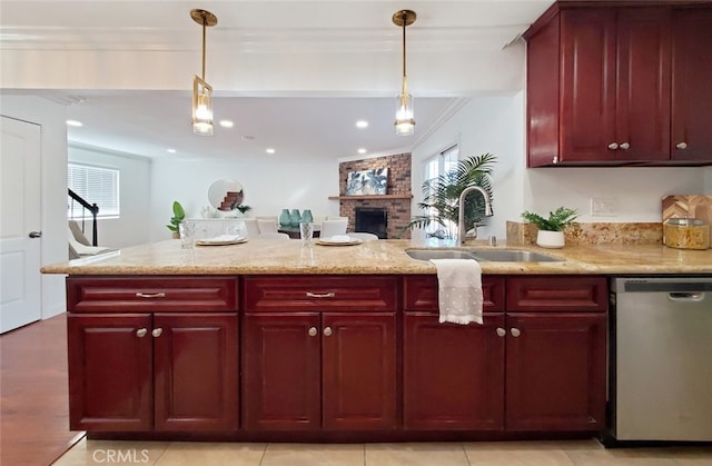 kitchen with a sink, dishwasher, reddish brown cabinets, a wealth of natural light, and a fireplace