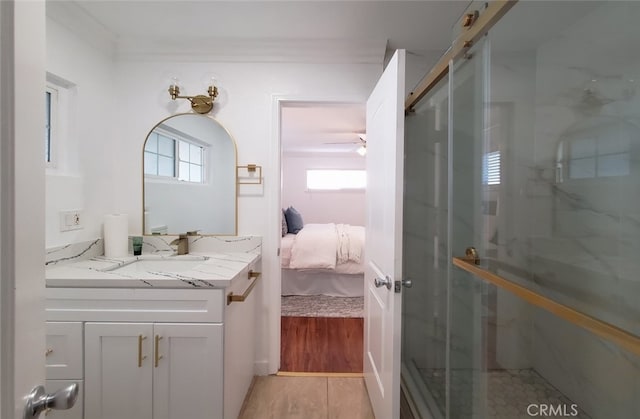 ensuite bathroom with a marble finish shower, vanity, a ceiling fan, crown molding, and ensuite bath