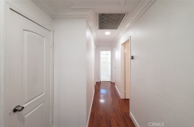 hall with dark wood finished floors, visible vents, crown molding, and baseboards