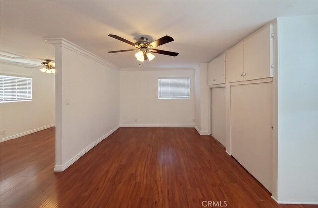 unfurnished bedroom featuring baseboards, a ceiling fan, wood finished floors, and multiple windows