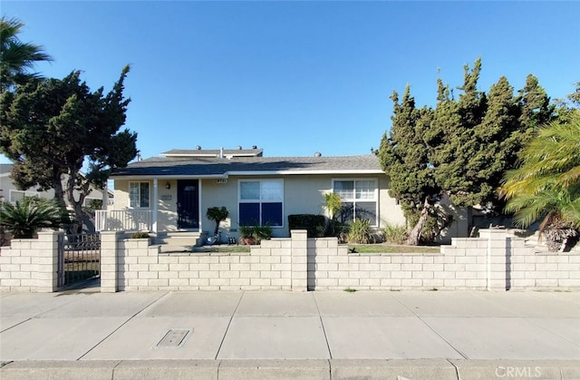 view of front facade featuring a fenced front yard, a gate, and stucco siding