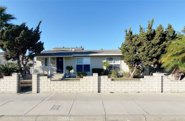 view of front of property featuring stucco siding, fence, and a gate