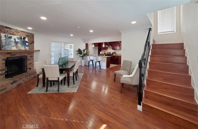 dining room featuring wood finished floors, recessed lighting, stairs, and crown molding