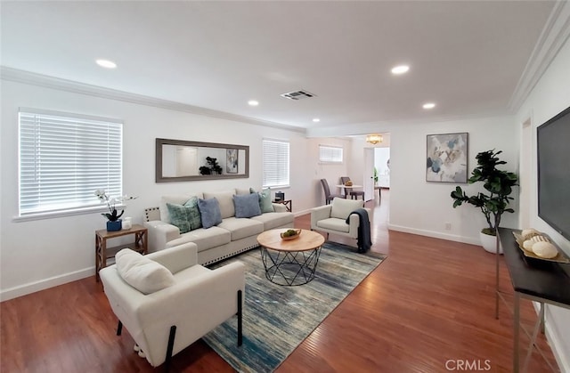 living area featuring baseboards, wood finished floors, visible vents, and ornamental molding