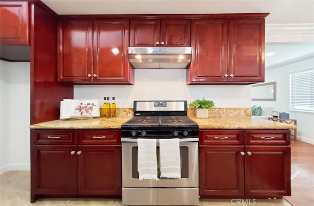 kitchen featuring gas stove, reddish brown cabinets, and under cabinet range hood