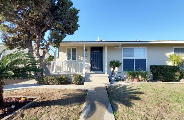 view of front facade with a porch, a front yard, and stucco siding