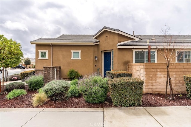 ranch-style home with stucco siding, fence, and a tile roof