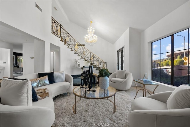 living area with a chandelier, visible vents, stairway, and a high ceiling