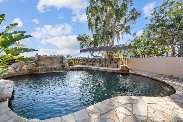 view of swimming pool with outdoor dry bar, a patio area, fence, and a fenced in pool