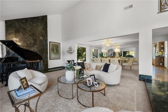 living area featuring a chandelier, a healthy amount of sunlight, visible vents, and a high ceiling