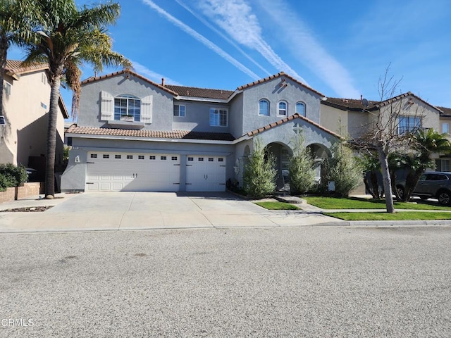 mediterranean / spanish home featuring a tile roof, an attached garage, concrete driveway, and stucco siding