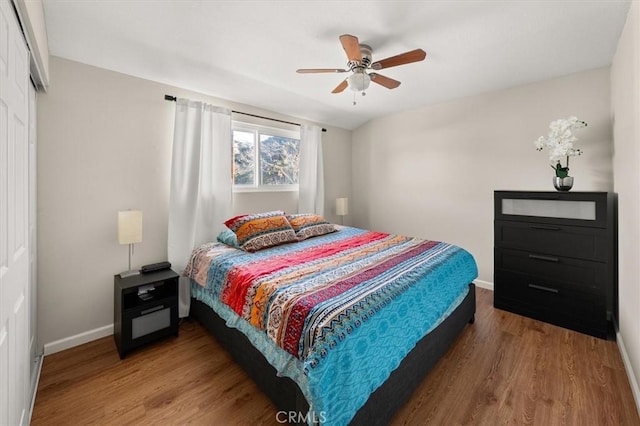 bedroom featuring ceiling fan, a closet, wood finished floors, and baseboards