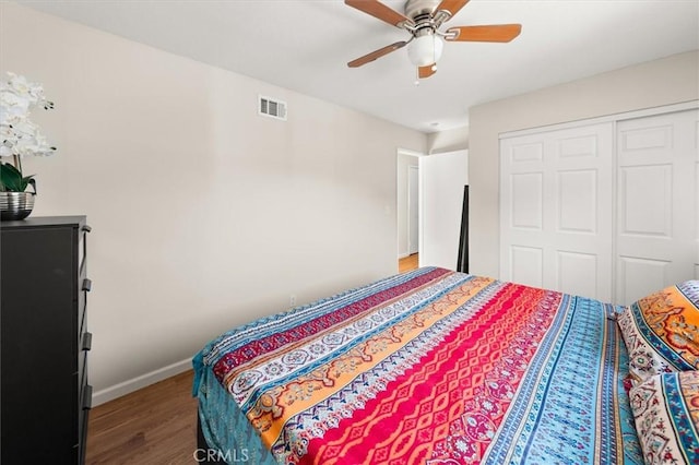 bedroom featuring a closet, visible vents, ceiling fan, wood finished floors, and baseboards