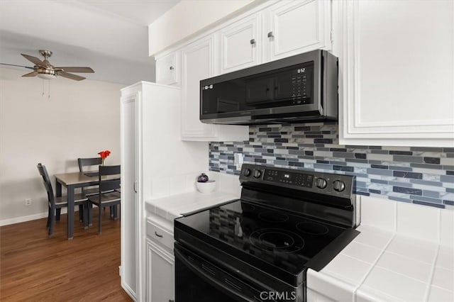 kitchen with white cabinetry, black / electric stove, decorative backsplash, and tile counters