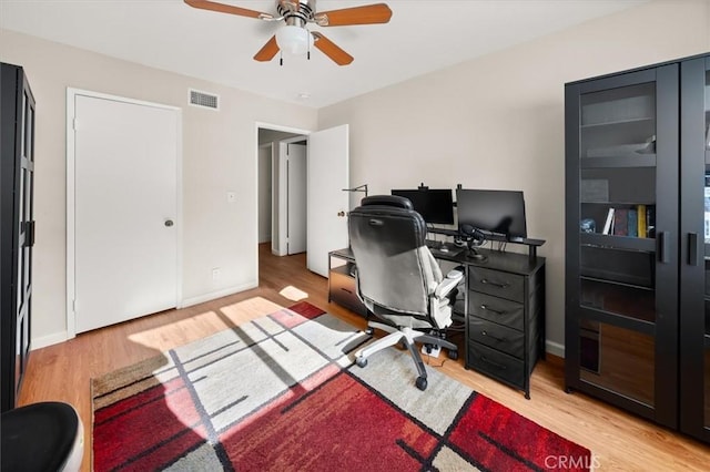 office area with light wood-style floors, baseboards, visible vents, and a ceiling fan