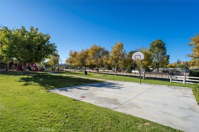 view of basketball court featuring community basketball court, fence, and a lawn