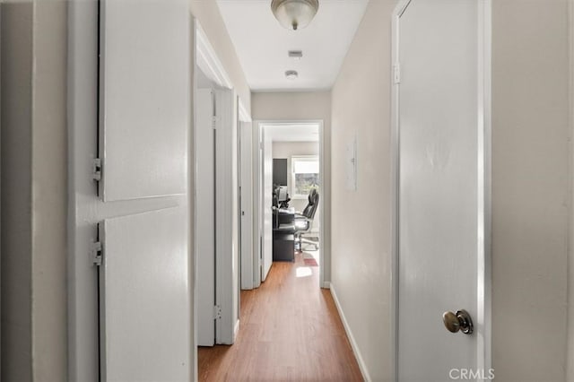 hall with light wood-type flooring and baseboards