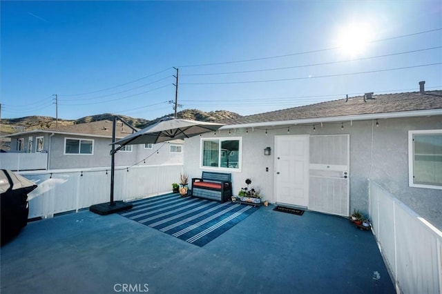 exterior space with a patio, roof with shingles, fence, and stucco siding