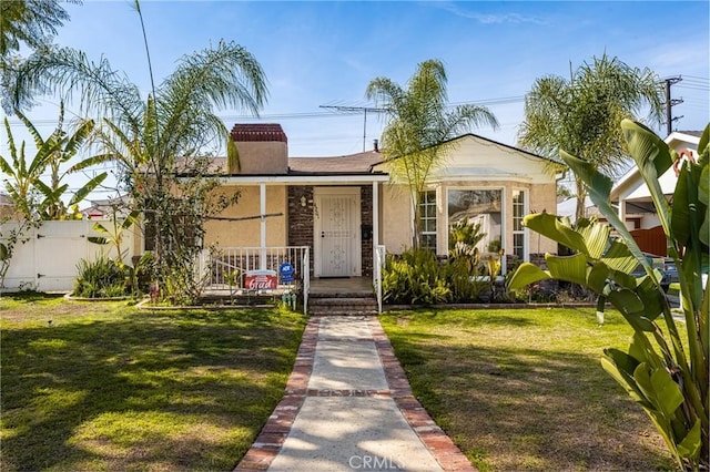 bungalow-style home with a front yard, fence, a chimney, and stucco siding