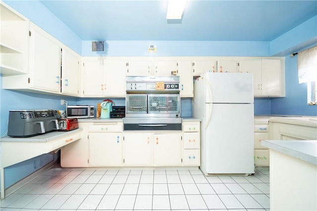 kitchen featuring visible vents, white cabinetry, light countertops, freestanding refrigerator, and stainless steel microwave