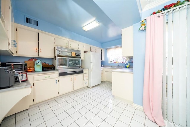 kitchen with visible vents, light countertops, stainless steel oven, and freestanding refrigerator