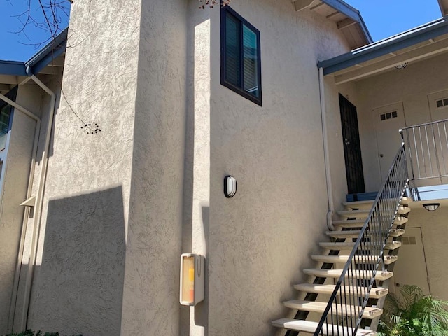 view of home's exterior with stairway and stucco siding