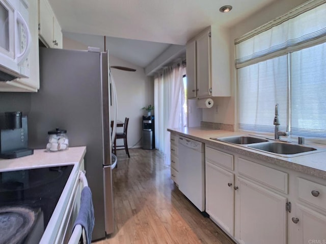 kitchen with white appliances, plenty of natural light, white cabinetry, and a sink