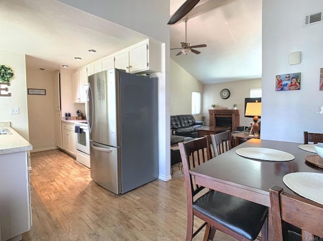 kitchen with electric range, a fireplace, visible vents, light countertops, and freestanding refrigerator