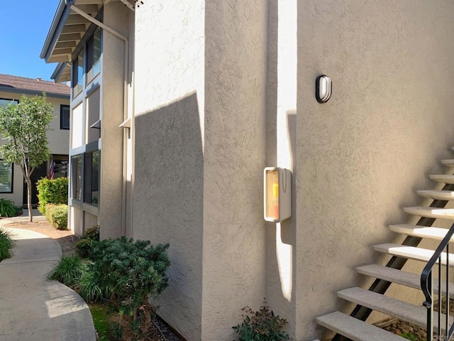 view of side of home featuring stairs and stucco siding