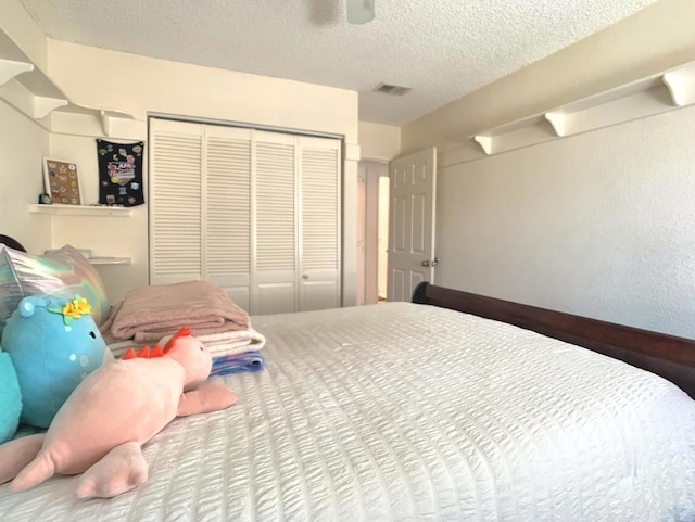 bedroom with ceiling fan, a textured ceiling, visible vents, and a closet