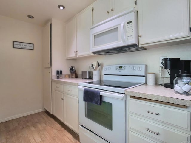 kitchen with white appliances, light countertops, and white cabinetry