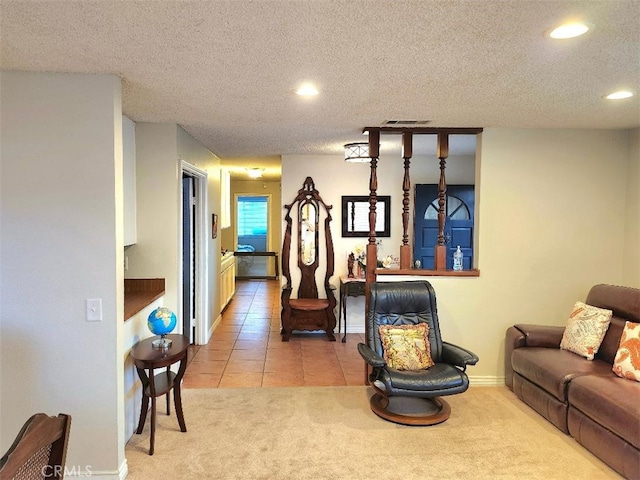 living area featuring light tile patterned floors, visible vents, a textured ceiling, and light colored carpet