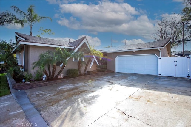 single story home featuring driveway, an attached garage, a gate, and stucco siding