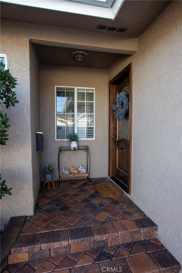 doorway to property with visible vents and stucco siding