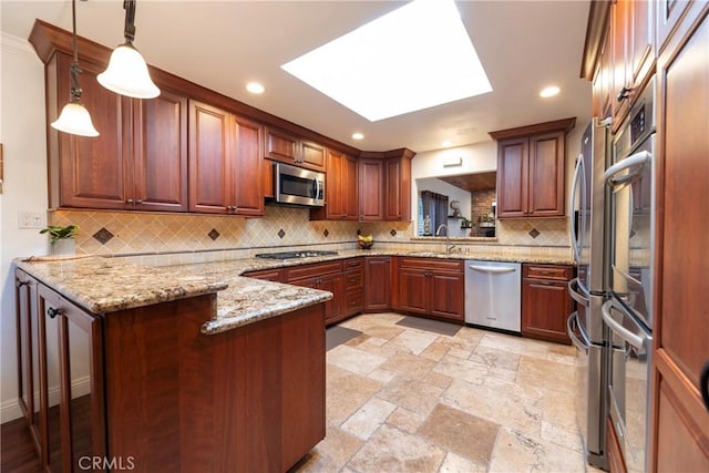 kitchen with decorative light fixtures, stainless steel appliances, a sink, light stone countertops, and a peninsula