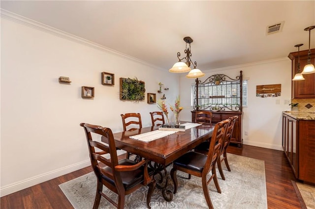 dining room with dark wood-style floors, visible vents, ornamental molding, and baseboards