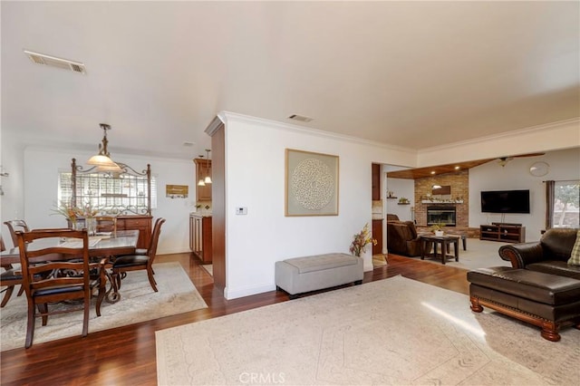 living room with dark wood-style floors, visible vents, and crown molding