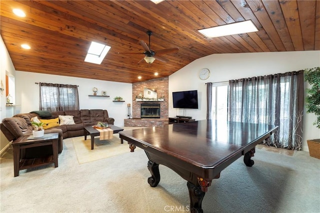 playroom featuring lofted ceiling with skylight, wood ceiling, ceiling fan, carpet, and a brick fireplace