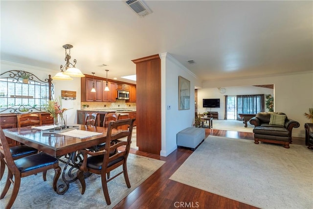 dining area featuring ornamental molding, dark wood-type flooring, visible vents, and baseboards