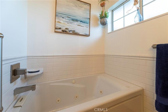 bathroom featuring a wainscoted wall and a whirlpool tub