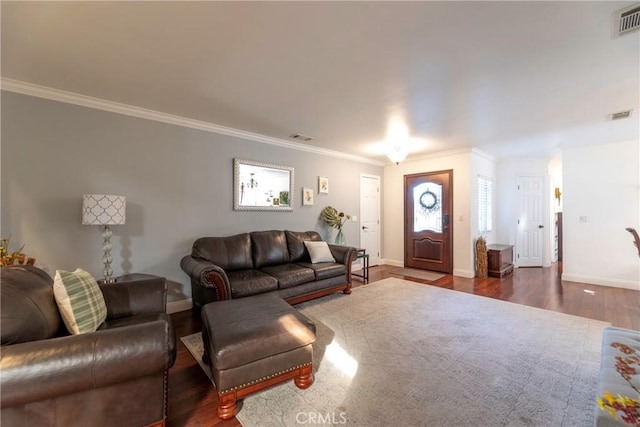 living area featuring ornamental molding, dark wood-type flooring, visible vents, and baseboards