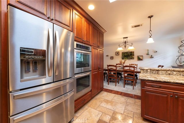 kitchen featuring decorative light fixtures, visible vents, appliances with stainless steel finishes, light stone countertops, and stone tile flooring