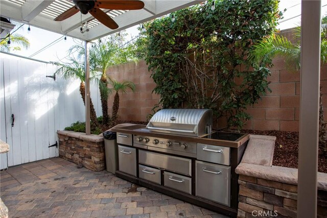 view of patio / terrace with ceiling fan, a grill, fence, and an outdoor kitchen