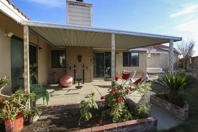 rear view of property featuring a patio area, fence, a chimney, and stucco siding