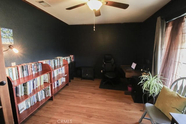 home office with a wealth of natural light, visible vents, ceiling fan, and light wood finished floors