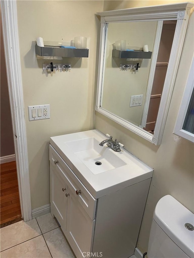 bathroom with toilet, tile patterned flooring, baseboards, and vanity