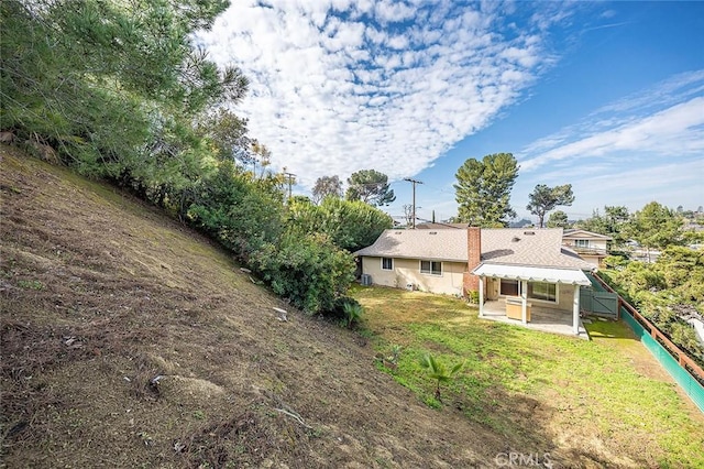 rear view of property featuring a patio area, a lawn, and fence