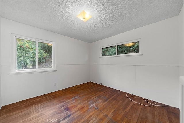 empty room with a textured ceiling and dark wood-style flooring